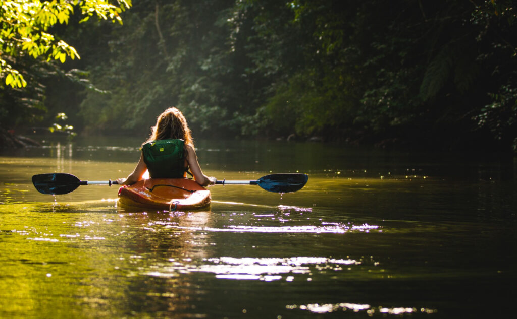 a woman peacefully kayaking in a calm lake