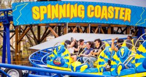 A thrilling spinning coaster ride at an amusement park, featuring vibrant colors and excited riders enjoying the experience.