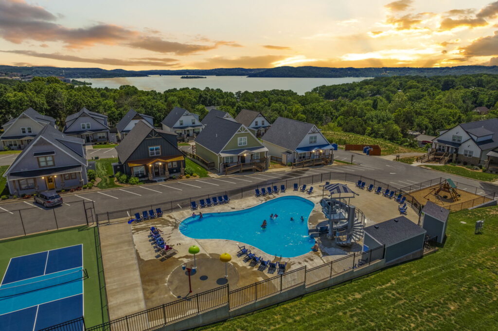 Sunset aerial of Branson Cove vacation rental lodges, outdoor pool with waterslide and pickleball court above Table Rock Lake