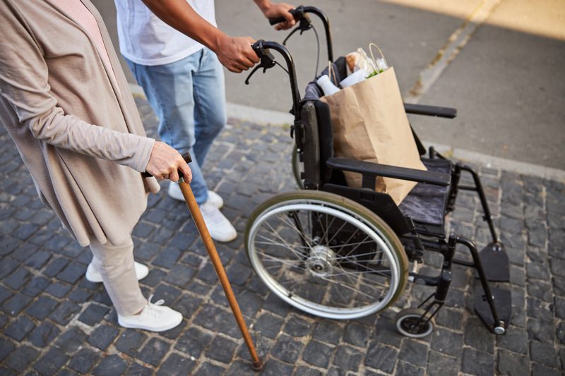 Family member assisting a grandparent with a wheelchair and cane while planning accessibility needs for a Branson trip