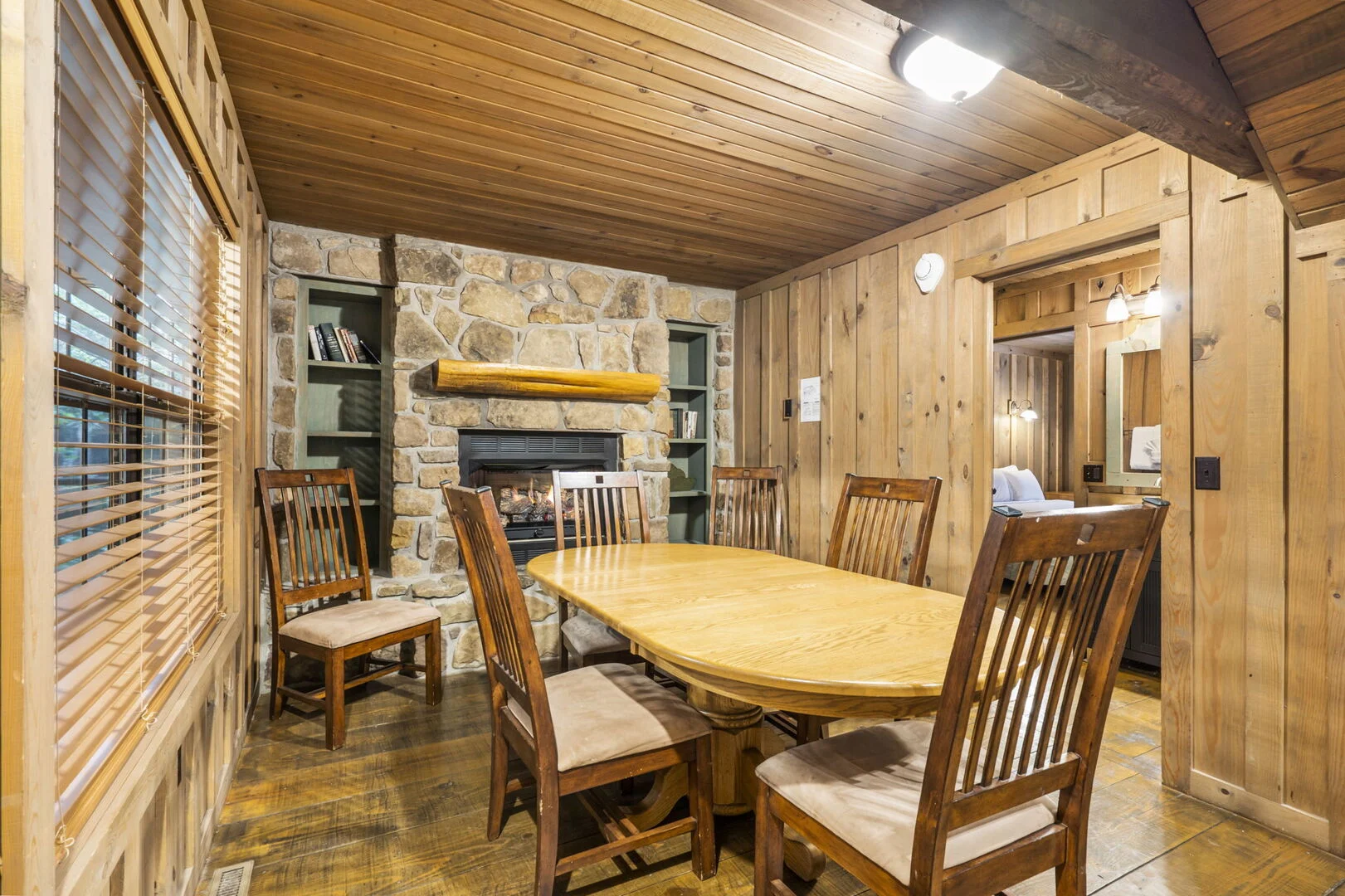 Wood-paneled dining room with a stone gas fireplace inside a Thousand Hills Vacations cabin near Branson, Missouri