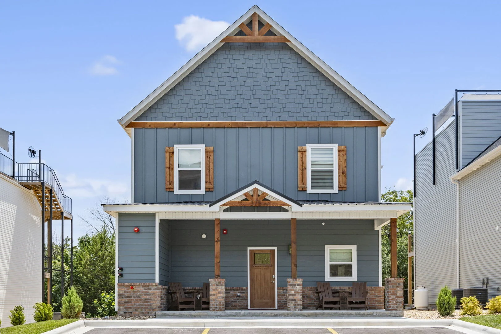 Two-story Branson vacation rental exterior with a covered porch and Adirondack chairs at Majestic at Table Rock