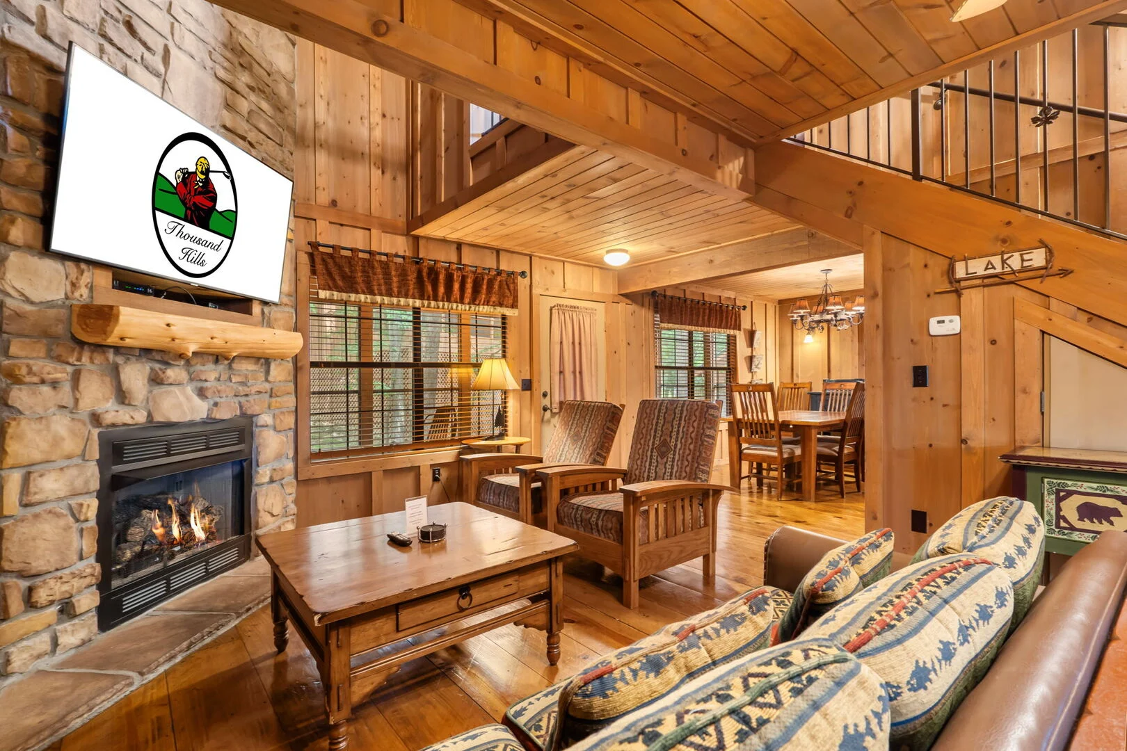Lit gas fireplace and mounted TV in the living room of a Thousand Hills Vacations cabin in Branson