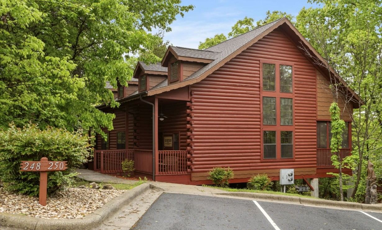 A log cabin rental near Branson, Missouri surrounded by trees, available after a day of hiking