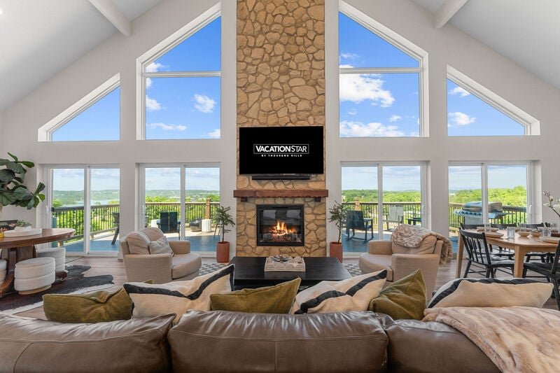 Great room with a stone fireplace and vaulted ceiling inside a seven-bedroom Wilderness Mountain lake home